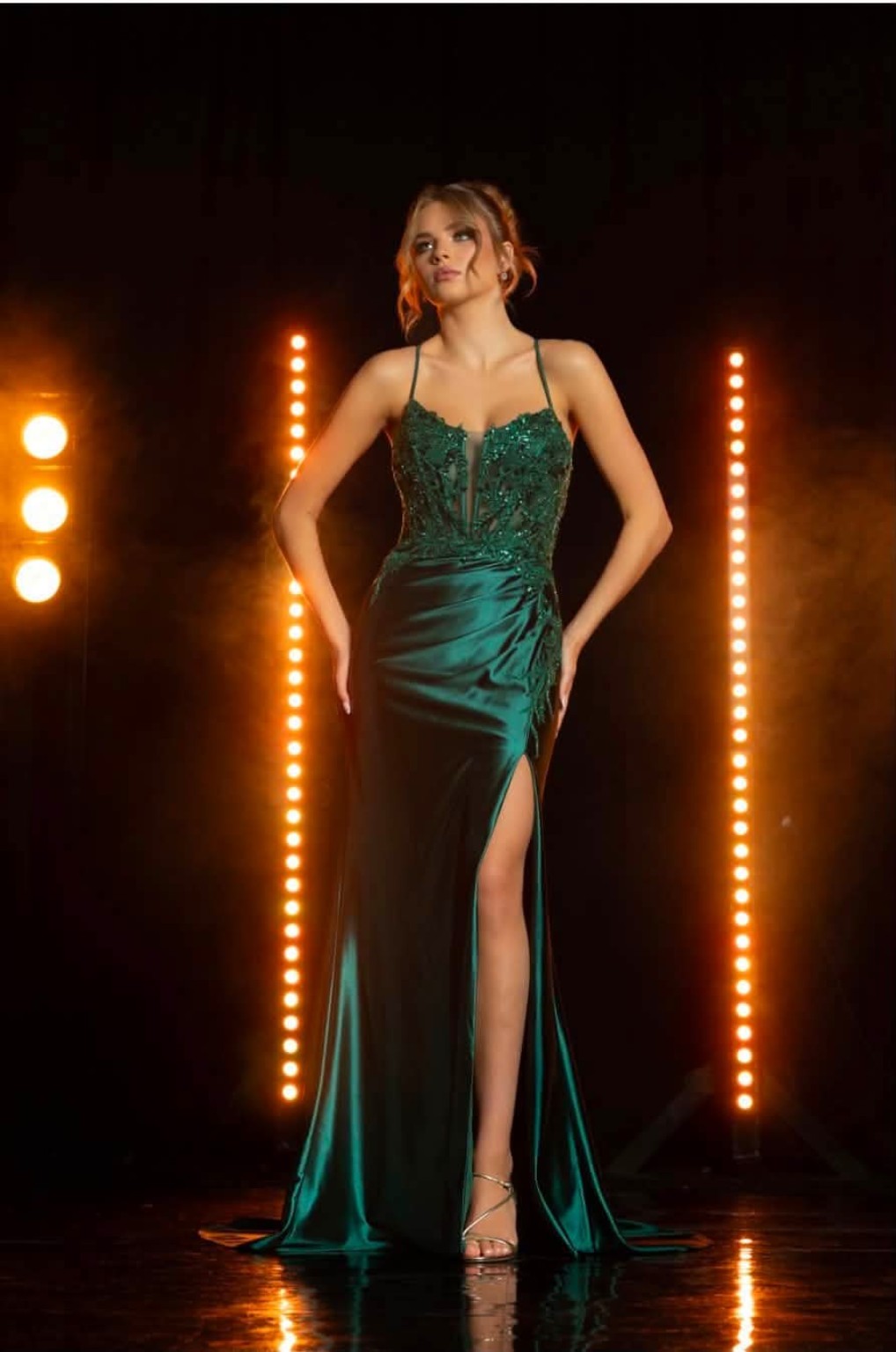 Fitted emerald gown beneath warm runway lights