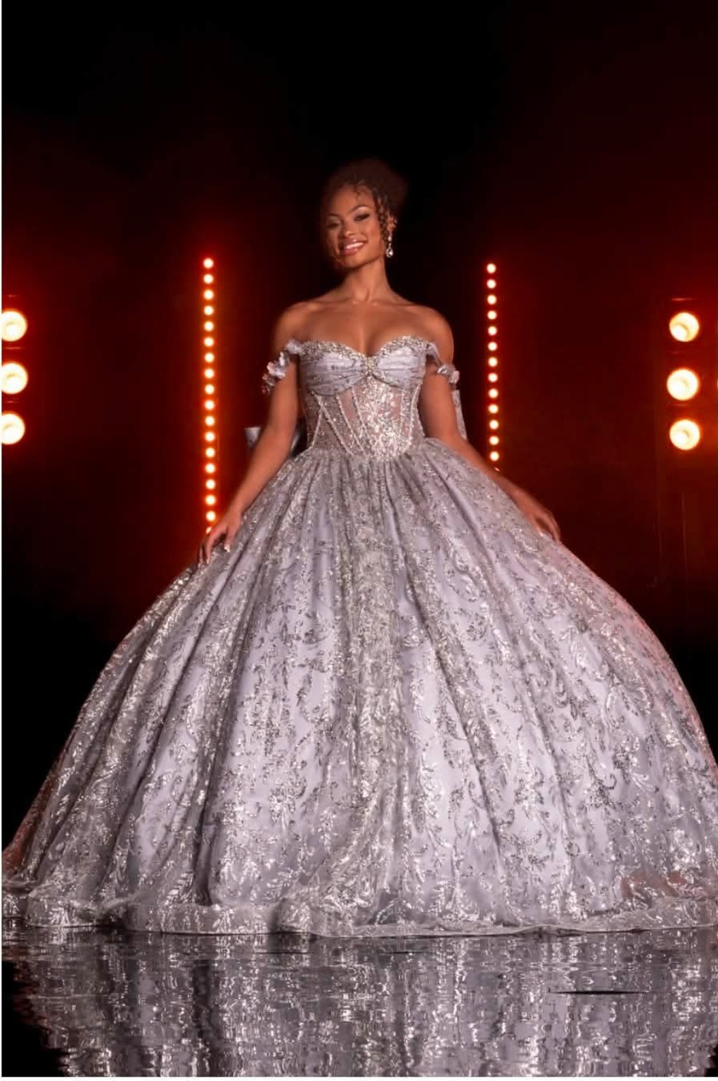 Model in an ornate silver ballgown under runway lights